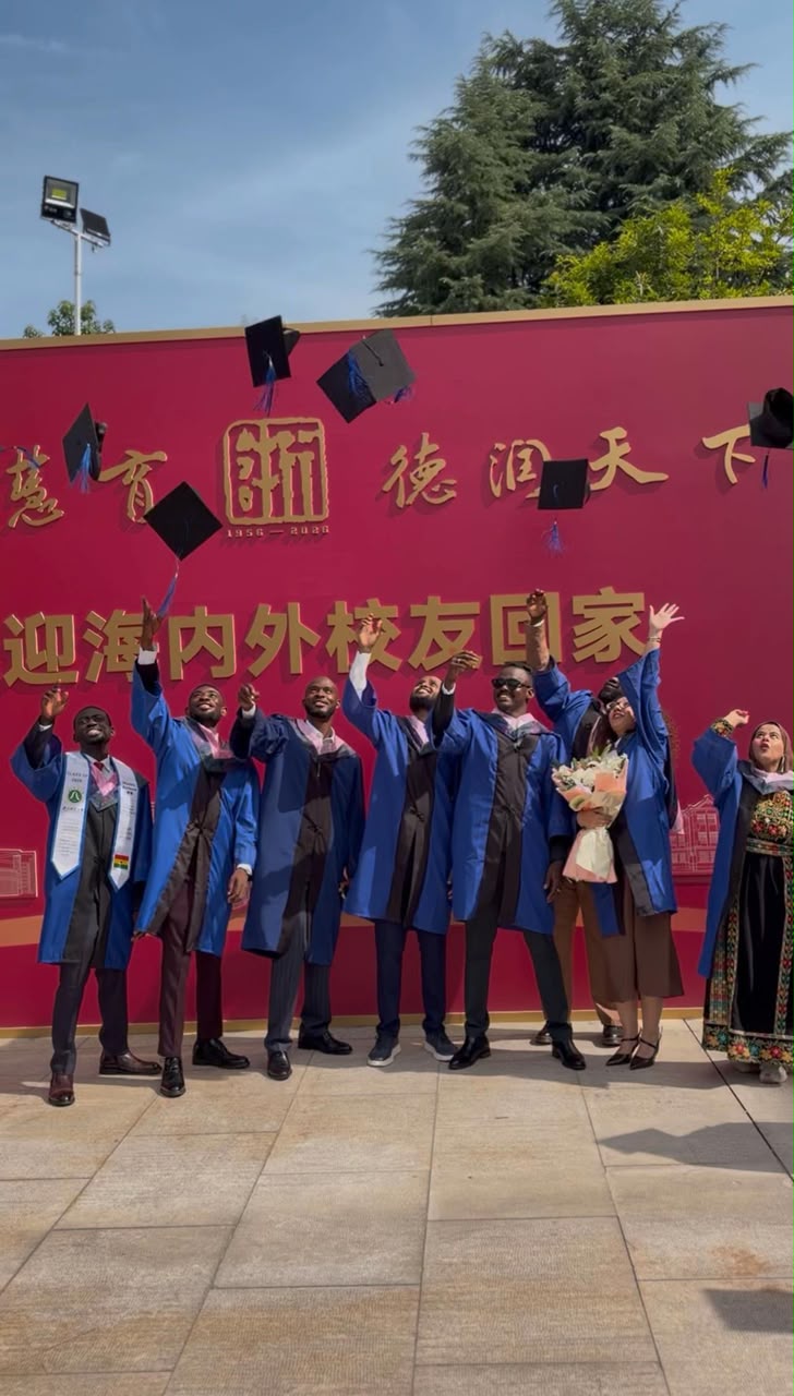 International graduates celebrating with caps in the air on campus