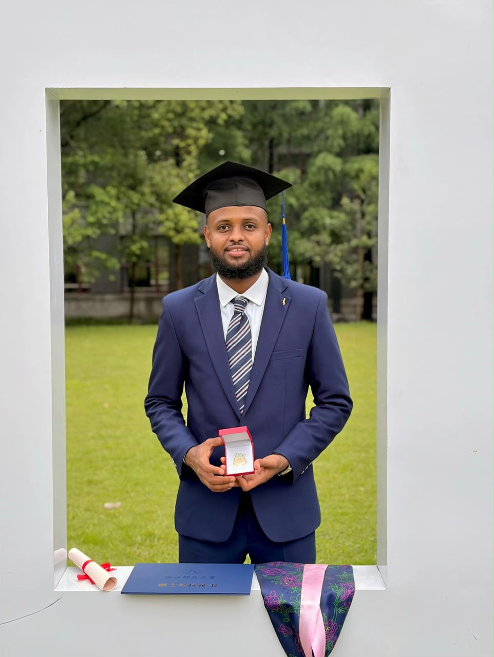 Formal graduation portrait with diploma folder and academic medal