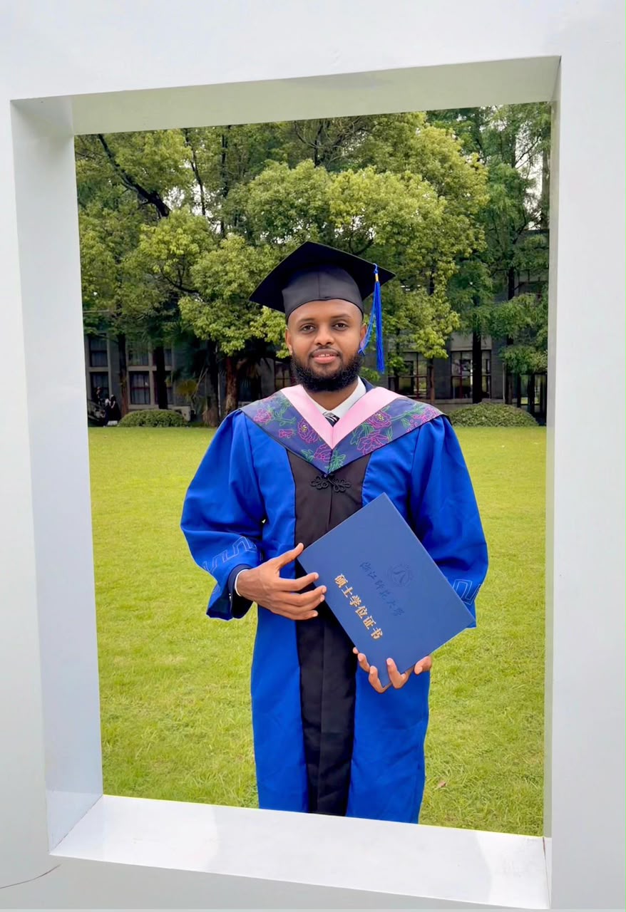 Graduate in full regalia with diploma on the university grounds